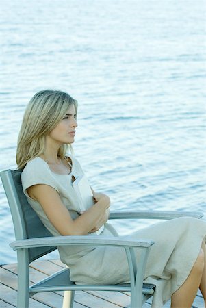Woman sitting on dock, holding book against chest Stock Photo - Premium Royalty-Free, Code: 632-01277244