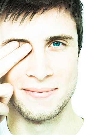 Young man holding fingers over eye, close-up, front view of face Fotografie stock - Premium Royalty-Free, Codice: 632-01277359