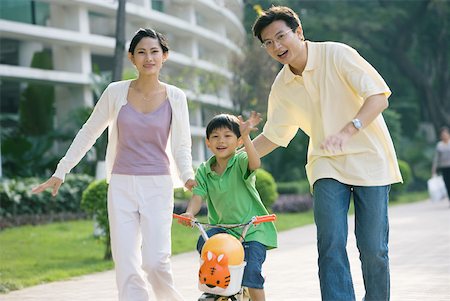 simsearch:696-03401224,k - Boy riding bicycle, parents on either side, waving at camera Stock Photo - Premium Royalty-Free, Code: 632-01270537