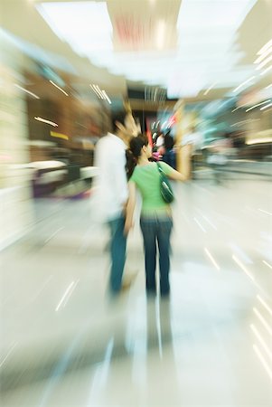 deformity - Couple walking through shopping mall, rear view, full length, blurred motion Foto de stock - Sin royalties Premium, Código: 632-01270550