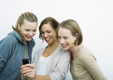 Young female friends looking at cell phone together Stock Photo - Premium Royalty-Free, Code: 632-01270647