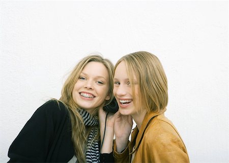 simsearch:632-01277233,k - Two young female friends sharing headphones, smiling at camera Fotografie stock - Premium Royalty-Free, Codice: 632-01270702