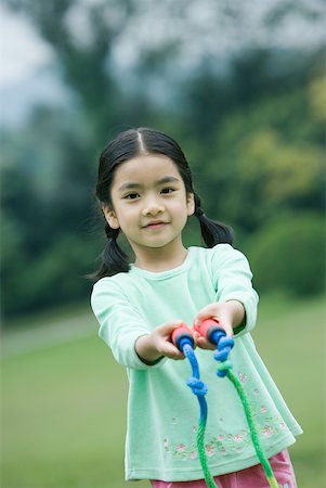 Little girl holding out jump rope toward camera Stock Photo - Premium Royalty-Free, Code: 632-01270715