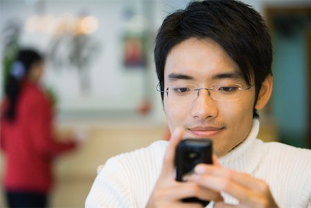simsearch:696-03401266,k - Young man looking at cell phone, smiling Fotografie stock - Premium Royalty-Free, Codice: 632-01270790