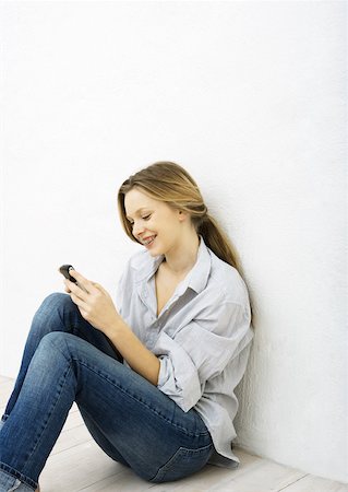 simsearch:632-01271195,k - Teenage girl using cell phone, sitting on floor Fotografie stock - Premium Royalty-Free, Codice: 632-01271195