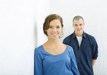 Young woman smiling at camera, young man behind her smirking Stock Photo - Premium Royalty-Free, Code: 632-01271595