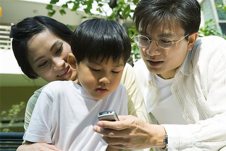 Boy with mother and father, father holding out cell phone for boy to see Foto de stock - Sin royalties Premium, Código: 632-01271781