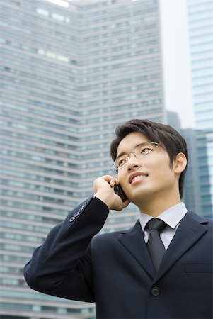 simsearch:695-05764533,k - Young businessman using cell phone, looking away, office building in background Foto de stock - Sin royalties Premium, Código: 632-01271834