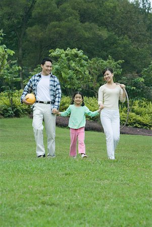 Girl walking across grass with parents Stock Photo - Premium Royalty-Free, Code: 632-01272068
