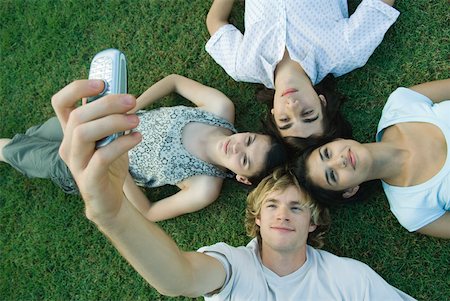 simsearch:693-06668076,k - Group of young friends lying on grass, heads together, one young man taking photo with cell phone Stock Photo - Premium Royalty-Free, Code: 632-01380146