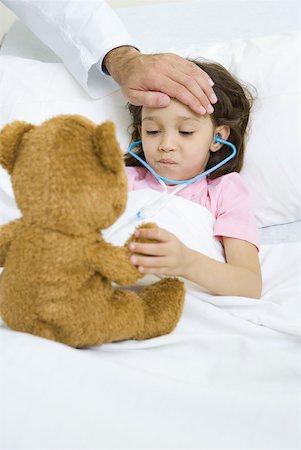 simsearch:632-01380299,k - Girl lying in hospital bed, holding teddy bear, doctor's hand on forehead Stock Photo - Premium Royalty-Free, Code: 632-01380260