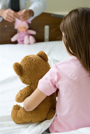 sitting teddy bear back view - Girl sitting in hospital bed holding teddy bear, facing doctor holding doll Stock Photo - Premium Royalty-Free, Code: 632-01380285