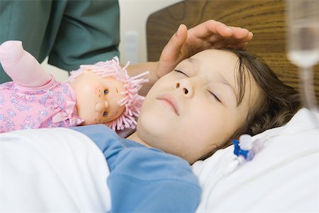 Girl sleeping in hospital bed, woman's hand posed over girl's forehead Stock Photo - Premium Royalty-Free, Code: 632-01380304