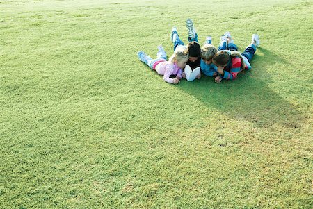 sneaking boy - Children lying on grass, reading book together Stock Photo - Premium Royalty-Free, Code: 632-01380316