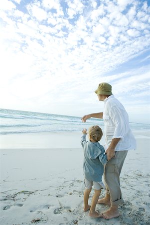 simsearch:696-03401542,k - Senior man standing on beach with grandson, pointing toward distance Foto de stock - Royalty Free Premium, Número: 632-01380373