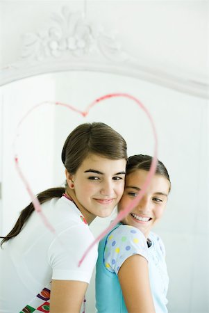 Two young female friends, reflected in mirror with heart drawn in lipstick Stock Photo - Premium Royalty-Free, Code: 632-01380409