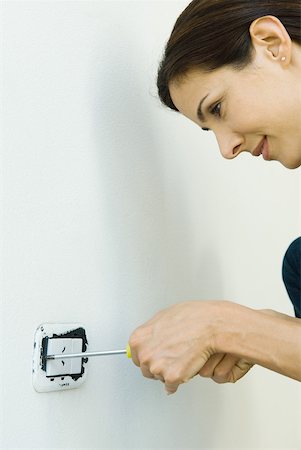 Woman removing lightswitch cover from wall Stock Photo - Premium Royalty-Free, Code: 632-01380549