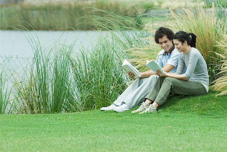simsearch:632-01271843,k - Young adult couple reading outdoors, sitting on grass by edge of lake Stock Photo - Premium Royalty-Free, Code: 632-01380556