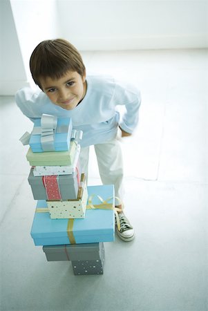Boy standing next to stack of Christmas presents Stock Photo - Premium Royalty-Free, Code: 632-01380631