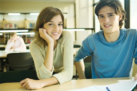 simsearch:632-01380712,k - College students sitting at table in library, smiling at camera Fotografie stock - Premium Royalty-Free, Codice: 632-01380728