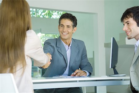 simsearch:695-03376535,k - Young couple sitting across desk from businessman, woman shaking hands with businessman Stock Photo - Premium Royalty-Free, Code: 632-01611870