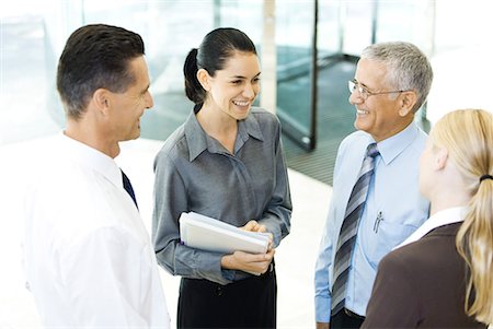 simsearch:632-01155443,k - Business associates standing in lobby, smiling at each other, chatting Fotografie stock - Premium Royalty-Free, Codice: 632-01612040