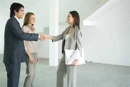 empty space for design - Real estate agent shaking hands with young couple in empty home interior Stock Photo - Premium Royalty-Free, Code: 632-01612729