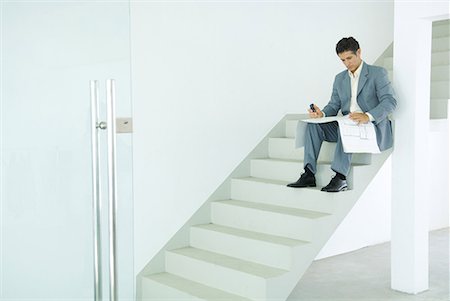 simsearch:696-03394263,k - Man sitting on stairs, looking at blueprints Foto de stock - Sin royalties Premium, Código: 632-01612720