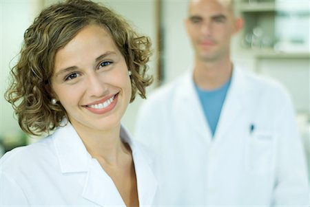 Female doctor smiling, male colleague in background, portrait Foto de stock - Sin royalties Premium, Código: 632-01612763