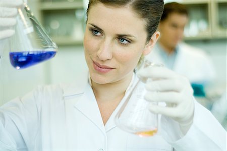 Young woman working in scientific laboratory, holding up flasks Stock Photo - Premium Royalty-Free, Code: 632-01612786