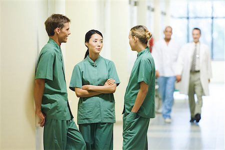 Three young medical colleagues standing in hallway, having discussion Stock Photo - Premium Royalty-Free, Code: 632-01613007