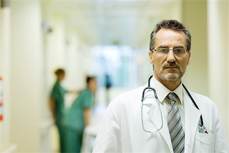 simsearch:632-03630033,k - Male doctor standing in hospital corridor, looking at camera, head and shoulders Stock Photo - Premium Royalty-Free, Code: 632-01613012