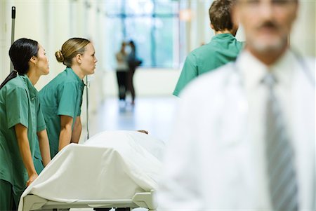 doctor patient bed side view - Medical staff pushing stretcher, looking away, doctor walking in foreground Stock Photo - Premium Royalty-Free, Code: 632-01613049