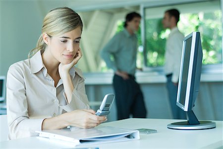 simsearch:632-08130262,k - Young businesswoman in office, using cell phone, looking down Stock Photo - Premium Royalty-Free, Code: 632-01613111