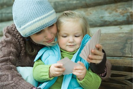 Teenage girl and toddler playing cards, dressed in winter clothing, cheek to cheek Stock Photo - Premium Royalty-Free, Code: 632-01613202
