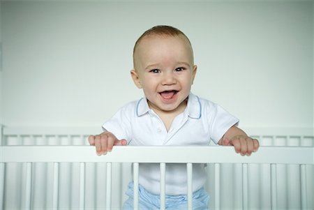 Baby standing in crib, smiling at camera Foto de stock - Sin royalties Premium, Código: 632-01613256