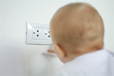 dangerous electrical pictures - Baby touching electric outlet, rear view Stock Photo - Premium Royalty-Free, Code: 632-01613262