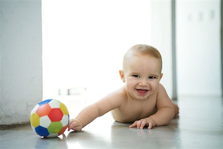 Baby lying on floor with ball, laughing and looking at camera Stock Photo - Premium Royalty-Free, Code: 632-01636922