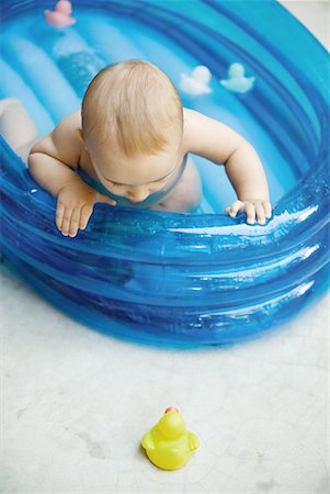Baby in inflatable baby pool looking at rubber dusk on ground Foto de stock - Sin royalties Premium, Código: 632-01637009