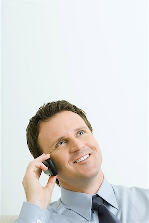 simsearch:695-03380514,k - Businessman using cell phone, smiling, looking up, portrait Fotografie stock - Premium Royalty-Free, Codice: 632-01638475