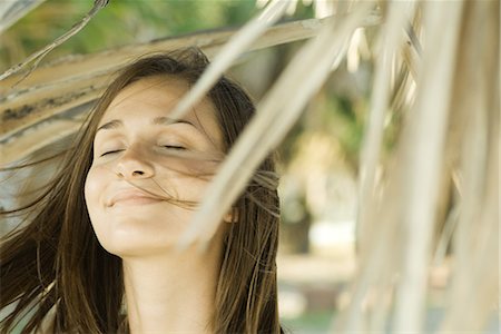 Femme entourée de feuillage sec, les yeux fermés, cheveux au vent, gros plan Photographie de stock - Premium Libres de Droits, Code: 632-01638570