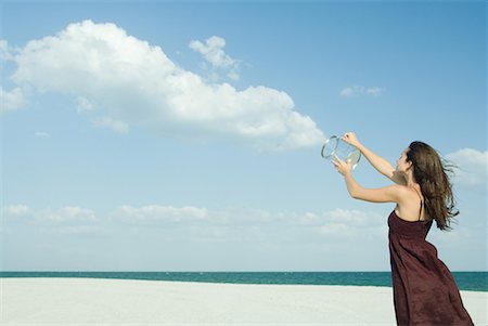 Woman standing on beach, holding up clear container, releasing clouds, optical illusion Foto de stock - Sin royalties Premium, Código: 632-01638584