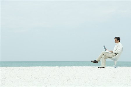 Businessman using laptop computer on the beach, full length Stock Photo - Premium Royalty-Free, Code: 632-01638663