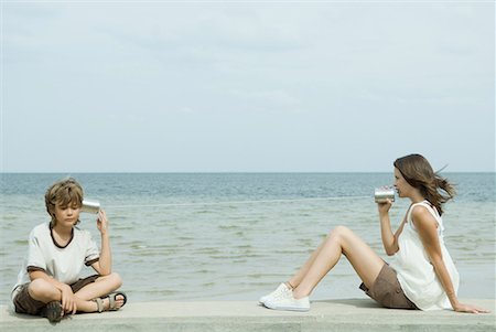 Boy and teen sister sitting next to water, talking to each other through tin can phone Foto de stock - Royalty Free Premium, Número: 632-01638690