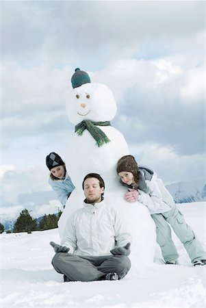picture of a girl sitting in padmasana - Young man meditating in front of snowman, two girls creeping up behind him Stock Photo - Premium Royalty-Free, Code: 632-01638778