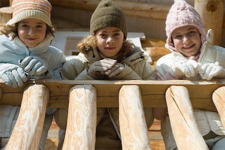 family in log cabin - Three preteen or teen girls standing on deck of log cabin, looking down at camera, low angle view Foto de stock - Sin royalties Premium, Código: 632-01785055