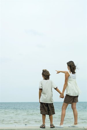 simsearch:696-03395430,k - Brother and sister holding hands and looking at ocean, rear view Foto de stock - Royalty Free Premium, Número: 632-01785096
