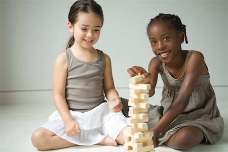 Two girls sitting on floor playing with blocks, one smiling at camera Stock Photo - Premium Royalty-Free, Code: 632-01785111