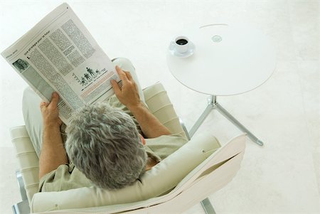 Man sitting, reading newspaper, high angle view Stock Photo - Premium Royalty-Free, Code: 632-01785177