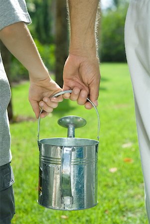 Cropped rear view of man and child carrying watering can together Stock Photo - Premium Royalty-Free, Code: 632-01785220